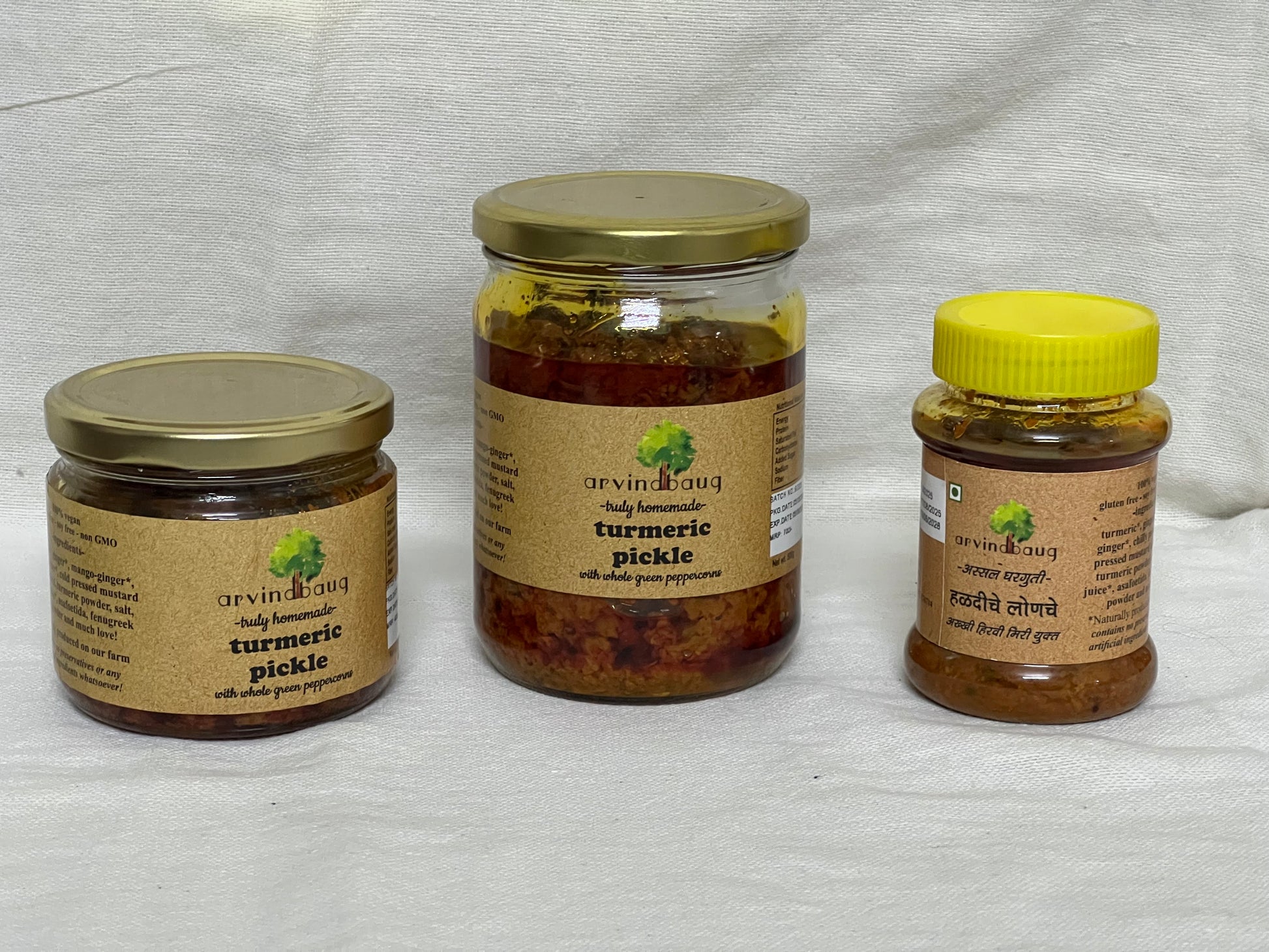200 g, 250 g, and 500 g jars of Arvindbaug turmeric pickle with whole green peppercorns.